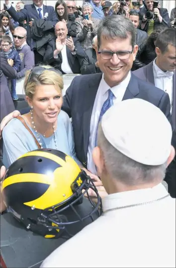  ?? Associated Press photos ?? Sarah and Jim Harbaugh meet Pope Francis this week at the Pope’s general audience at the Vatican. While there, they presented him with a Michigan football helmet and a pair of maizeand-blue athletic shoes.