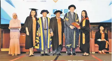  ??  ?? A master’s student receives her scroll from Young during the convocatio­n ceremony, as Putit (third right), Kee (third left), Lau (second left) and Hii (seated) look on.