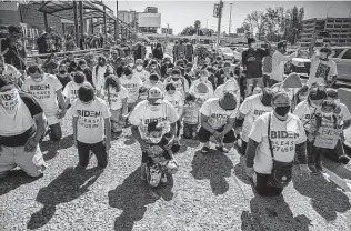  ?? Zuma Press / Tribune News Service ?? A group of migrants wearing T-shirts that read, “Biden, please let us in,” kneel and pray Tuesday at the border crossing in San Ysidro, Mexico.