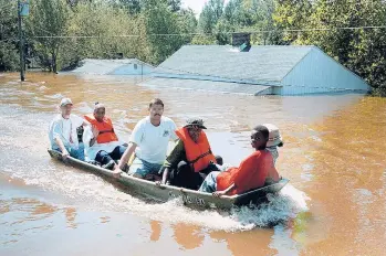  ?? ALAN MARLER/AP 1999 ?? A boat with residents of Princevill­e, N.C., travels down Main Street after the Tar River flooded the town.