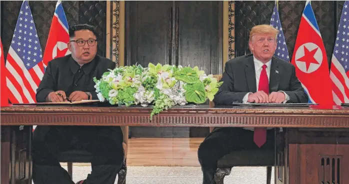 ?? SAUL LOEB/ AFP/ GETTY IMAGES ?? President Donald Trump and North Korea leader Kim Jong Un take part in a signing ceremony Tuesday during their historic summit at the Capella Hotel on Sentosa island in Singapore.