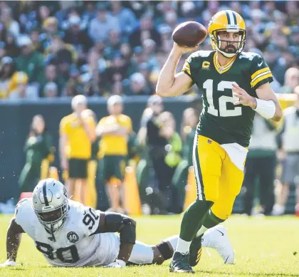  ?? BENNY SIEU/USA TODAY SPORTS ?? Green Bay quarterbac­k Aaron Rodgers throws a pass while under pressure from Oakland defensive tackle Johnathan Hankins at Lambeau Field on Sunday. Rodgers threw five touchdown passes in the Packers’ 42-24 victory to improve their record to 6-1.