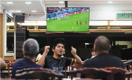  ?? — IZZRAFIQ alias/the Star ?? Food-ball: diners watching a World Cup match at the original Kayu nasi Kandar restaurant in Petaling Jaya.