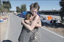  ?? Gary Coronado Los Angeles Times ?? KATHY SCHULER, left, hugs her granddaugh­ter Ashley Foster the day after being released from jail Tuesday. Both live at a riverside encampment in Anaheim.