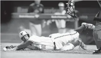  ?? GAIL BURTON/ASSOCIATED PRESS ?? Adam Jones reaches for the plate to score the winning run in the 10th inning as Rockies catcher Nick Hundley can’t catch a low throw from pitcher Jordan Lyles — who had trouble with a soft hit by Manny Machado.