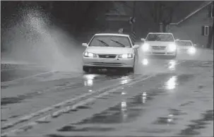  ?? The Sentinel-Record/Richard Rasmussen ?? POOLING WATER: Cars drive through pools of water in the 3700 block of Park Avenue on Friday.