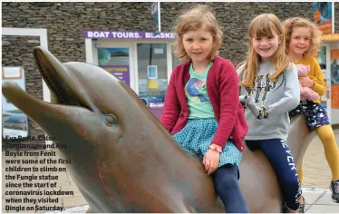  ??  ?? Eva Boyle, Chloe Stephenson and Ava Boyle from Fenit were some of the first children to climb on the Fungie statue since the start of coronaviru­s lockdown when they visited Dingle on Saturday.