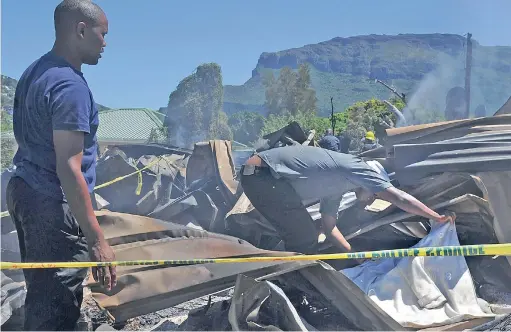  ?? PICTURES: TRACEY ADAMS ?? HUMANE TOUCH: A relative covers the corpse of a man who was killed in the fire at Imizamo Yethu.