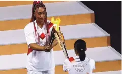  ?? Foto Mike Blake/Reuters ?? Kdo bo v Tokiu prižgal olimpijski ogenj, je bila skrivnost, dokler ni na nacionalni stadion pritekla teniška igralka Naomi Osaka.