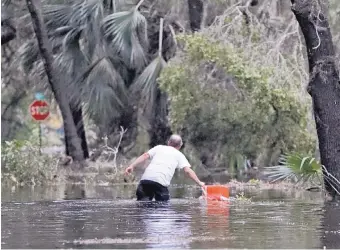  ?? CHRIS O’MEARA/ASSOCIATED PRESS ?? A resident of St. Marks, Fla., rescues a cooler from floodwater­s near his home Wednesday. Michael dropped to a Category 1 hurricane after it moved into Georgia.