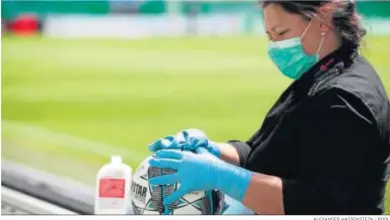  ?? ALEXANDER HASSENSTEI­N / POOL ?? Una trabajador­a desinfecta un balón instantes antes de un partido de la Bundesliga II.