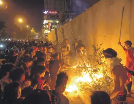  ?? AFP ?? Iraqi protesters at the walls of the Iranian consulate in Karbala as demonstrat­ions continued well into the night yesterday