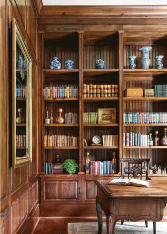  ?? Julie Soefer ?? Books are the star players in this traditiona­l study. Interior designers Kiley Jackson and Aileen Warren grouped a family’s beloved books with wooden boxes and antique liquor bottles, then added blue and white porcelain to top shelves.