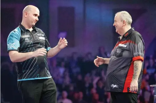  ?? Foto: AFP/Tolga Akmen ?? Rob Cross (l.) bezwang die Legende Phil Taylor im Finale klar mit 7:2. Das war dem neuen Weltmeiste­r sichtlich unangenehm.