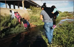  ?? MARIO TAMA/GETTY IMAGES ?? Migrants cross the border between the U.S. and Mexico at the Rio Grande River, as they walk to enter El Paso, Texas, on May 19, as seen from Ciudad Juarez, Mexico. The location is in an area where migrants frequently turn themselves in and ask for asylum in the U.S. after crossing the border.