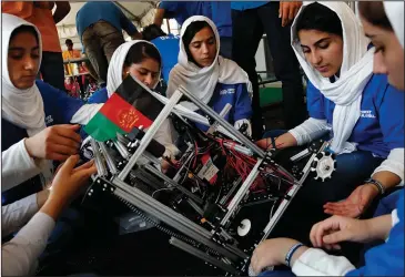  ?? The Associated Press ?? GIRL ROBOT SQUAD: Lida Azizi, right, and other members of the Afghanista­n team make a repair to their robot after their first round competing in the FIRST Global Robotics Challenge on Monday in Washington. The challenge is an internatio­nal robotics...