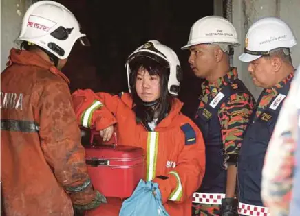  ?? SHAHRIL BADRI SAALI
PIC BY MOHAMAD ?? Lim Yi Jun with Fire and Rescue Department personnel after retrieving items from her house yesterday.