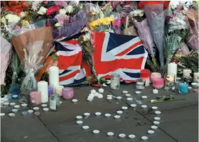  ?? AP PHOTO ?? Flowers and candles are seen after a vigil in Albert Square, Manchester, England, on Tuesday – the day after the suicide bomb attack at an Ariana Grande concert left 22 people dead.