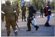  ?? (AP/Alexei Alexandrov) ?? A man evacuated from the Mariupol steel mill walks to a bus under the eye of Russian soldiers and Donetsk People’s Republic militiamen on Friday as the last of the civilians holed up in the plant were moved out.