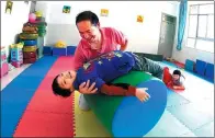  ?? LIN YIGUANG / XINHUA ?? Special education teacher Dai Jianrong helps a disabled child complete sensory integratio­n training in Kunming, Yunnan province.