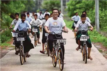  ?? AFP PIC ?? Mike Than Tun Win (centre) cycling with students on the outskirts of Yangon on Tuesday.