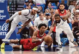  ?? ?? Rockets forward Amen Thompson, center, tries to grab a loose ball from Mavericks point guard Kyrie Irving, right, during the first half Sunday in Dallas.