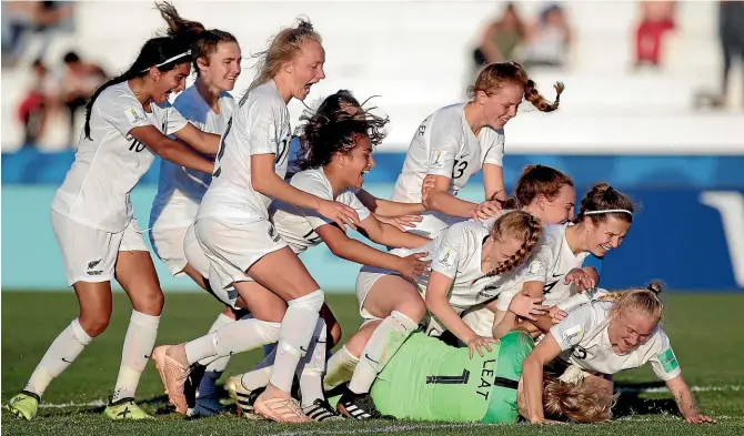  ?? AP ?? Delighted Football Ferns youngsters swamp goalkeeper Anna Leat, bottom, after Leat scored the matchwinni­ng penalty in a dramatic shootout win over Japan that put New Zealand into the semifinals of the Under-17 World Cup in Uruguay.