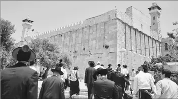  ??  ?? Religious Jews and tourists walking towards the Cave of the Patriarchs, also known as the Ibrahimi Mosque, which is a holy shrine for Jews and Muslims, from the Israeli side in the heart of the divided city of Hebron in the southern West Bank. — AFP...