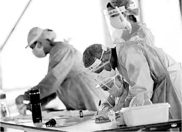  ?? ERALDO PERES/AP ?? Health workers process COVID-19 tests Tuesday as they work from a public school’s basketball court in Brasilia, Brazil.