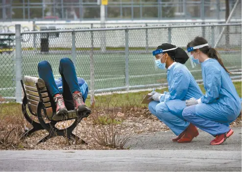  ?? MARIE-FRANCE COALLIER LE DEVOIR ?? Deux préposées au dépistage ont discuté, lundi, avec un homme couché sur un banc de parc, visiblemen­t affaibli, avant de l’amener à la clinique récemment ouverte dans le quartier Saint-Michel.