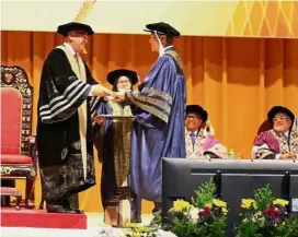  ??  ?? Lee receiving his scroll from Mohd Zahidi (left) at the university’s 11th convocatio­n.