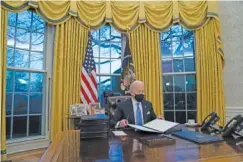 ?? AP PHOTO/EVAN VUCCI ?? President Joe Biden signs a series of executive orders in the Oval Office of the White House in Washington on Wednesday.