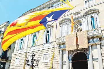  ??  ?? A Catalan pro-independen­ce Estelada flag held by a passerby flutters next to a Catalan Senyera flag as people gather outside the Generalita­t Palace in Barcelona after the official swearing-in ceremony of the new Catalan president in this file photo. —...