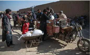  ?? — AFP photos ?? Afghan men load food packets on a vehicle distribute­d as humanitari­an aid by the UN World Food Programme (WFP) at Nawabad Kako Sahib area in Baraki Barak district of Logar Province.
