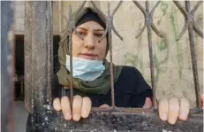 ?? — AFP ?? Tahani al Rifi looks out of her house’s gate in Gaza City, amid restrictio­ns imposed during the pandemic which have made travelling for treatment to a hospital in the West Bank impossible for her.