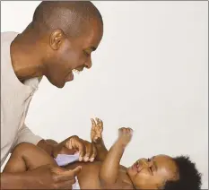  ??  ?? Young fathers are now spending more time with their children and even changing nappies