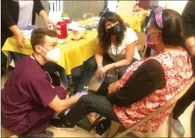  ?? MIKE URBAN - READING EAGLE ?? Drexel University College of Medicine at Tower Health student Paul Scalzo and Reading Hospital street medicine team member Jodylynn Mill, center, examine the feet of Gladis Morales of Reading during Wednesday’s free health fair for seniors.