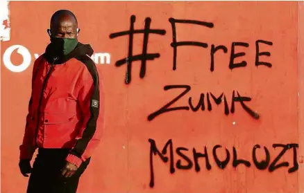  ?? Siphiwe Sibeko/Reuters ?? Homem em frente a grafite com as palavras “Zuma livre” em Vosloorus, na África do Sul