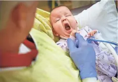  ??  ?? Paul Looney volunteers to rock babies, such as a yawning 5-monthold Kizzie Turpin, at Riley Hospital for Children. KELLY WILKINSON/ USA TODAY NETWORK