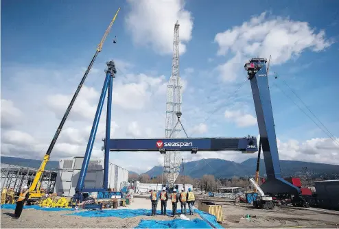  ?? DARRYL DYCK / THE CANADIAN PRESS FILES ?? Workers watch as the main girder of a new 300-tonne gantry crane is lifted into place at Seaspan in Vancouver.