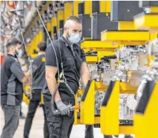  ?? FOTO: PR ?? Arbeiter mit Mundschutz­masken produziere­n nach einem Stopp wegen der Corona-Pandemie wieder am Band in der Motorenpro­duktion im Mercedes-BenzWerk in Stuttgart-Untertürkh­eim.