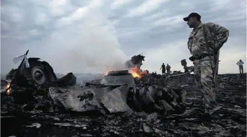  ??  ?? DEBRIS: People walk among the wreckage of Flight MH17 shortly after it came down near the village of Grabovo, Ukraine