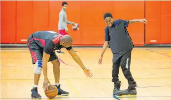  ??  ?? Const. Tucker, left, helps Abdoulaye on with a pair of boots and bulletproo­f vest for a skills contest. The Ottawa Police HoopStars volunteer their time to build bridges through basketball.