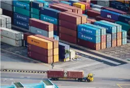  ??  ?? A truck transporti­ng shipping containers drives past stacked containers at Tanjong Pagar Container Terminal, operated by PSA Internatio­nal Pte, at the Port of Singapore in Singapore. (Bloomberg file photo)