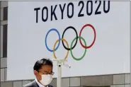  ?? KOJI SASAHARA — THE ASSOCIATED PRESS FILE ?? In this March 25, 2020, file photo, a man walks in front of a Tokyo Olympics logo at the Tokyo metropolit­an government headquarte­rs building in Tokyo.