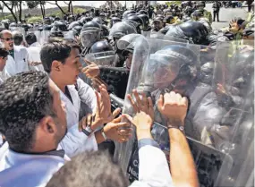  ??  ?? Marcha. Médicos venezolano­s forcejean con miembros de la Policía Nacional Bolivarian­a durante una protesta en Caracas.