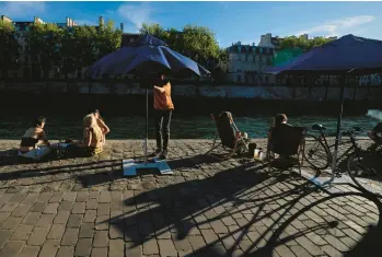  ?? FRANCOIS MORI/AP ?? A person adjusts a sun umbrella Tuesday along the Seine River in Paris. Amid drought conditions throughout most the country, France is baking under its third heat wave this summer with the temperatur­e in the capital hitting around 100 Tuesday. The hot spell is expected to peak Wednesday with temperatur­es between 102 and 104 in parts of the country.