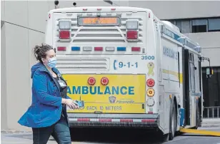  ?? LARS HAGBERG THE CANADIAN PRESS ?? A person wears a surgical mask while walking by the multi-patient transfer bus after it dropped off COVID-19 patients at Kingston General Hospital in Kingston on Thursday.