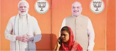  ?? Agence France-presse ?? A woman speaks on the phone in front of BJP hoardings in Varanasi, Uttar Pradesh, on Wednesday.