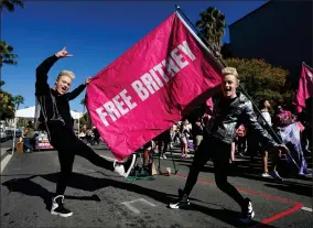  ?? AP PHOTO BY CHRIS PIZZELLO ?? Twins Edward, right, and John Grimes of Dublin, Ireland, hold a “Free Britney” flag outside a hearing concerning the pop singer’s conservato­rship at the Stanley Mosk Courthouse, Friday, Nov. 12, 2021, in Los Angeles.